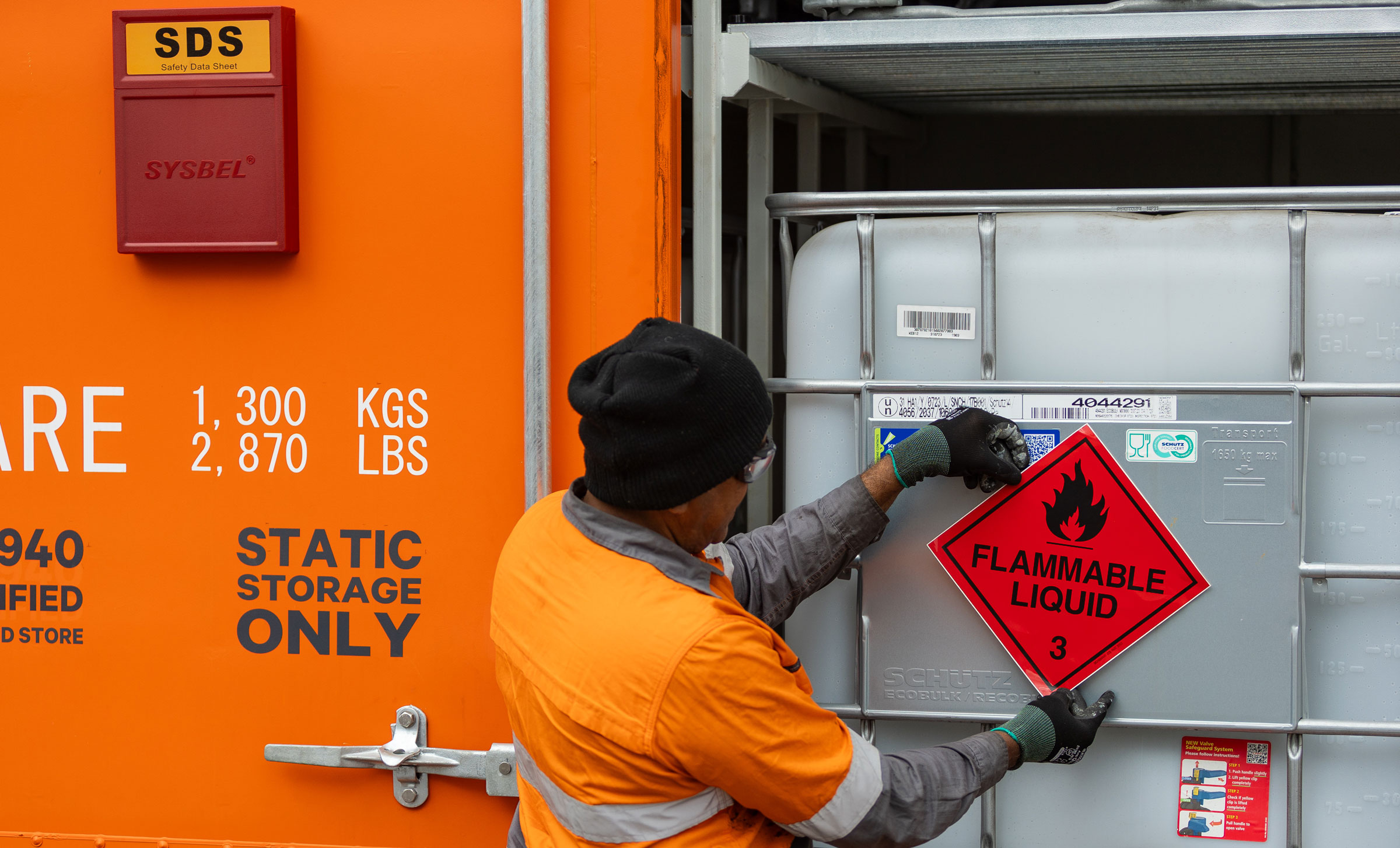 SCF worker placing a class 3 flammable liquid label on an IBC inside a Dangerous Goods Cabinet
